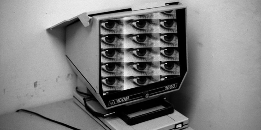 Black and white image of a mosaic of eyes on an old monitor.