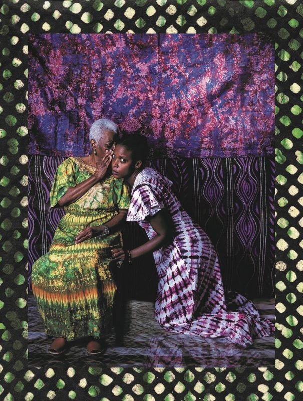 Older woman whispering into the ear of a younger woman kneeling beside her