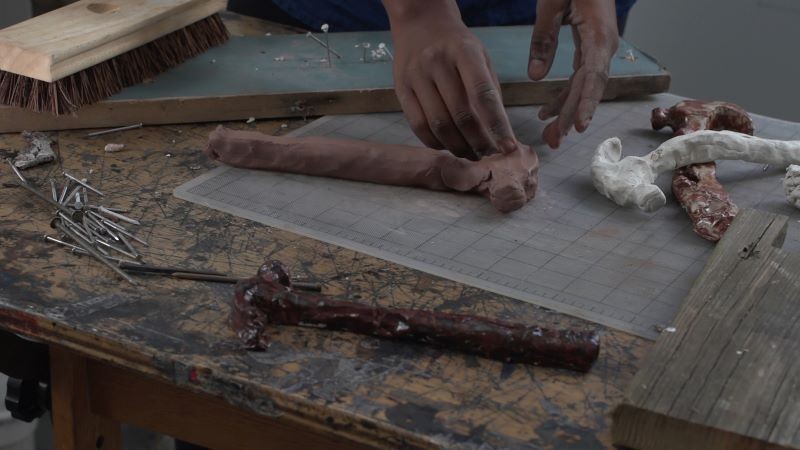 Hands molding a tool made out of clay