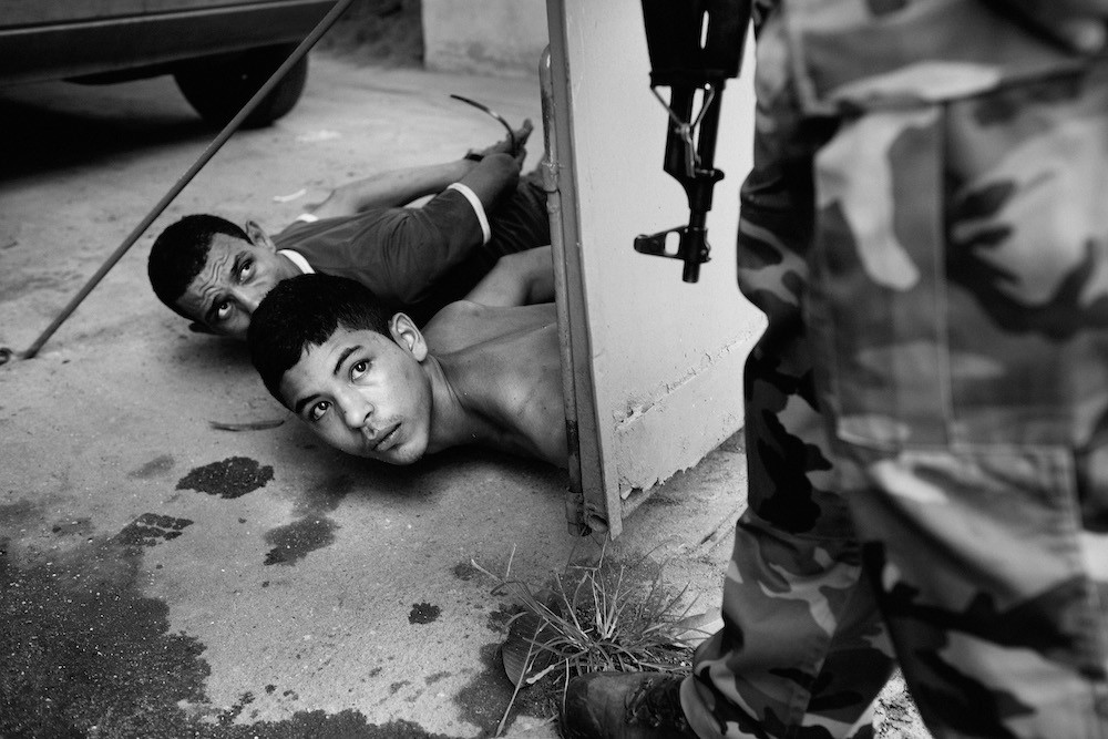 Two suspected drug traffickers (the closest being 15 years old) are arrested during a police operation in the Acari slum in northern Rio de Janeiro, Brazil, February 2008. Courtesy the artist. Joao Pina
