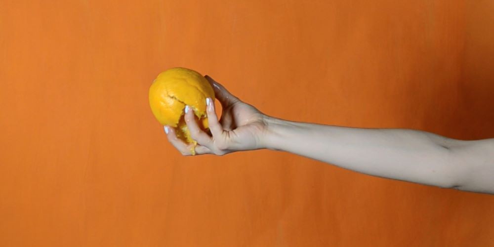 Tamar Ettun, still from It’s Not a Question of Anxiety, 2014. Hand squeezing an orange.