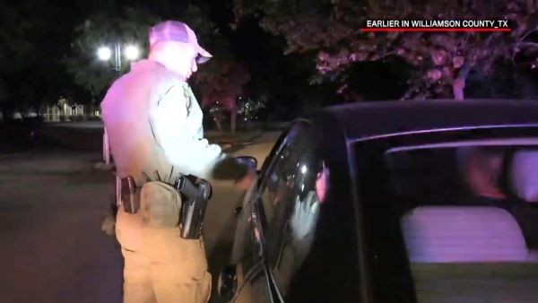 Still of a video of an armed individual speaking to the driver of a car