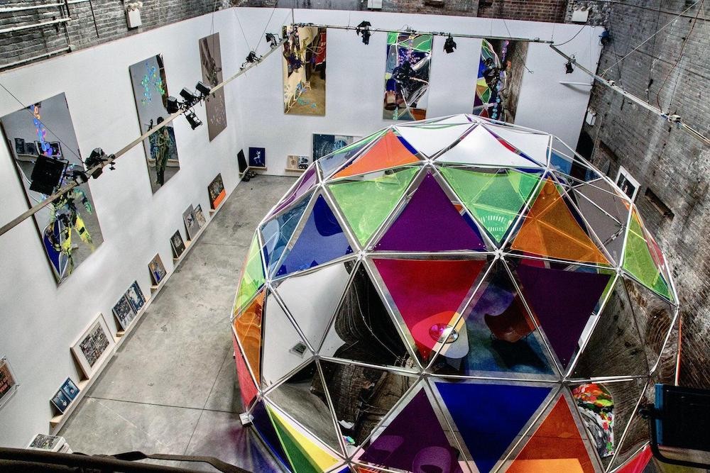 Tomas Vu-Daniel, 'The Man Who Fell to Earth,' installation view at the Boiler, NYC with plexiglas and aluminum dome, 2022 Room full of brightly colored artwork (prints and sculptures)