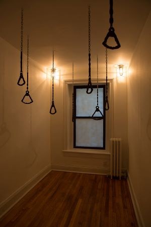 Chains hanging from the ceiling of a narrow room with a window