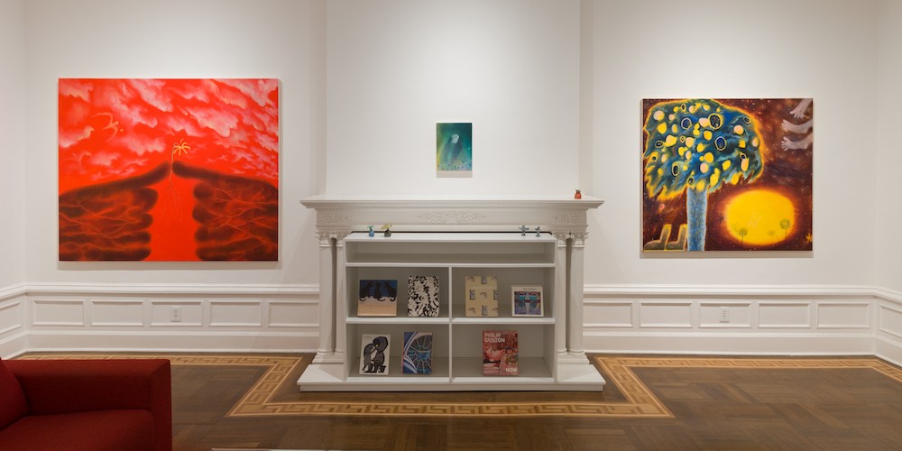 A wall in an apartment, with a fireplace flanked by two large paintings. 