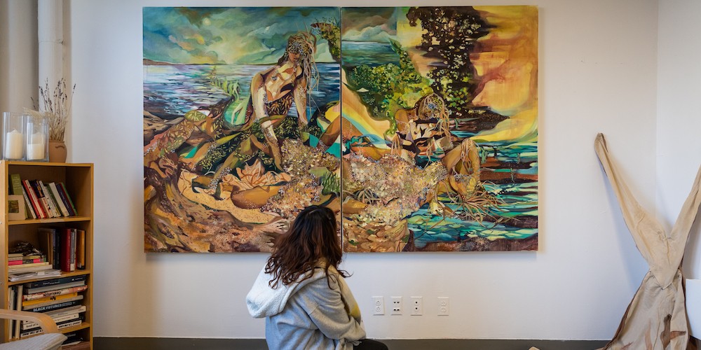 A woman kneels in front of a large painting