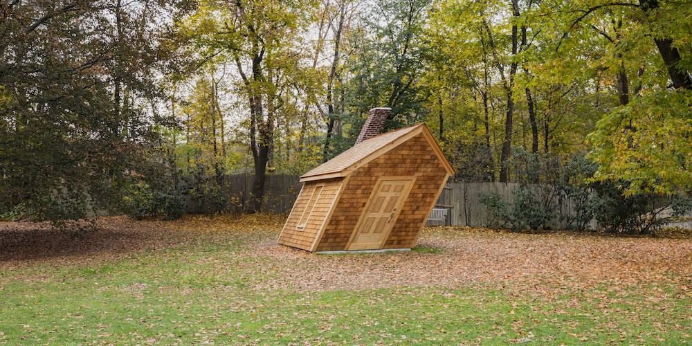 Small, slanted wooden cabin amongst trees, "Huff and a Puff" by Hugh Hayden '18
