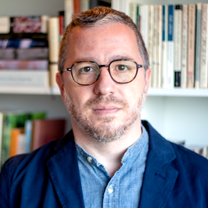Headshot of man with glasses in front of a bookshelf