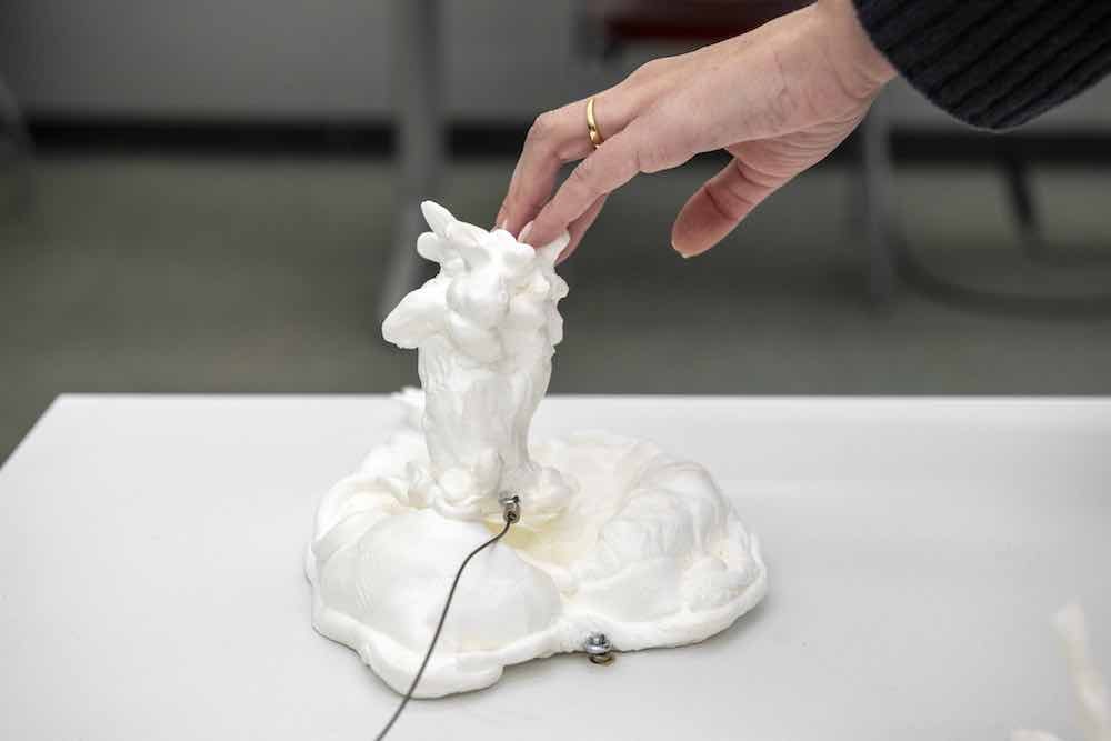 Hand touches sclupture.