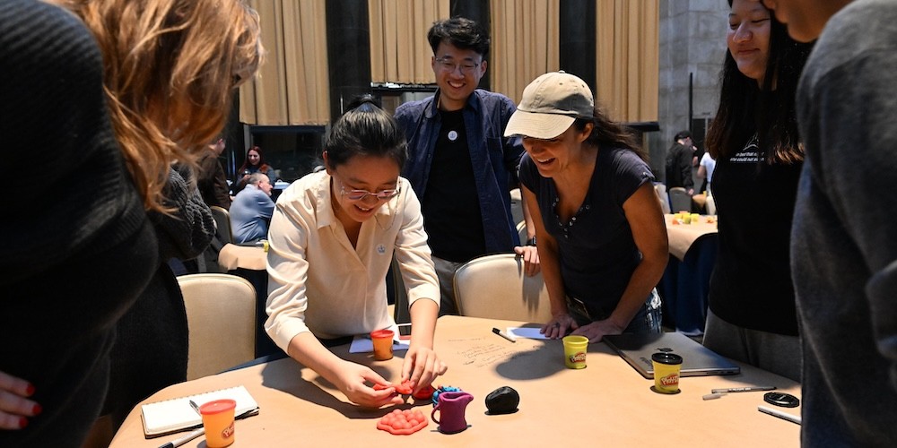 People gather around a table while utilizing play dough. 