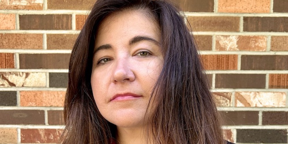 Close-up headshot of a woman in front of a brick wall: Professor Chloé Cooper Jones