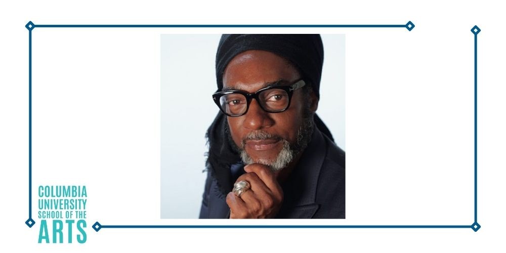 A Black man in a head wrap with black glasses and a goatee. 