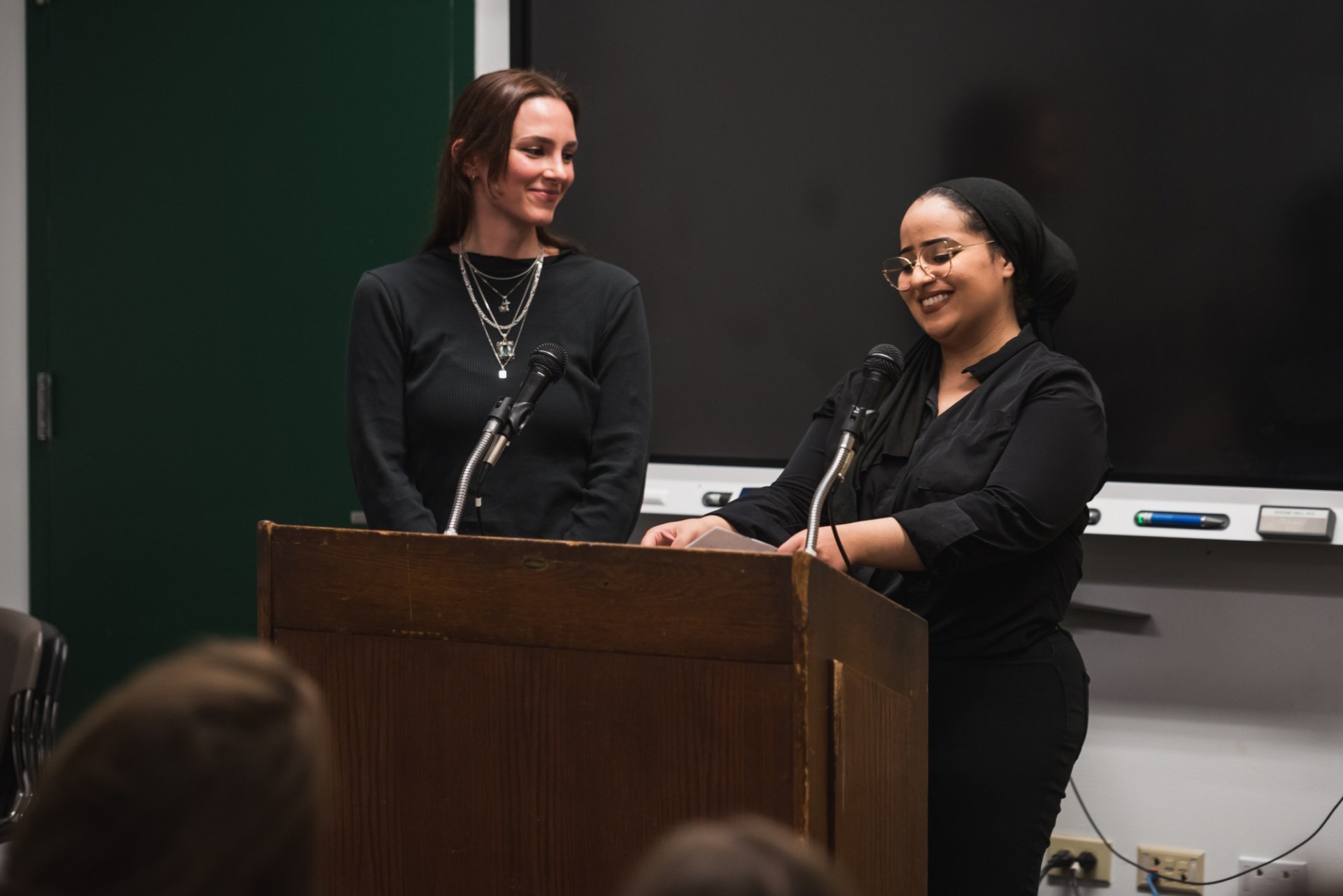 two women stand at a podium