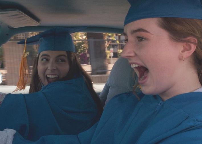 Teen women in a car with grad outfits screaming in joy