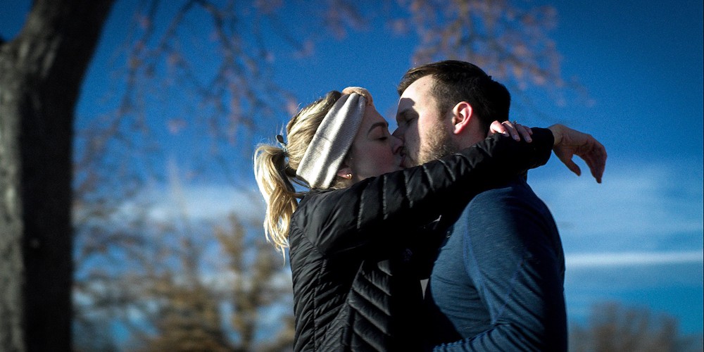 A man and a woman kissing outside.