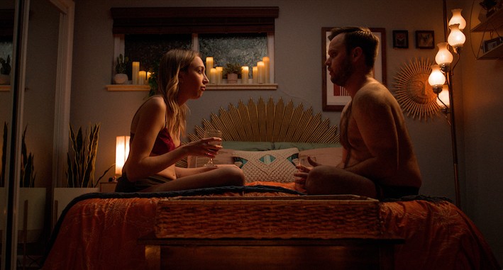 A couple sitting in bed together candle-lit room 