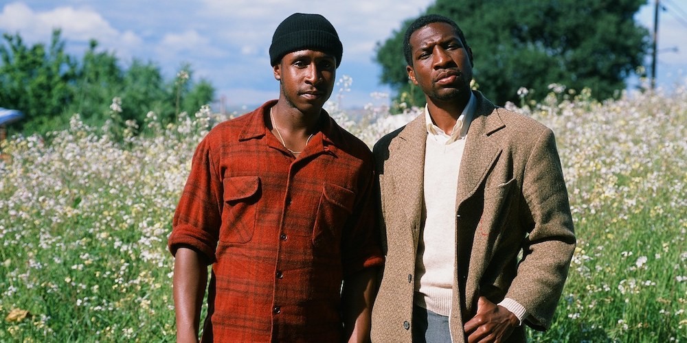 Two Black men standing in a field looking pensive