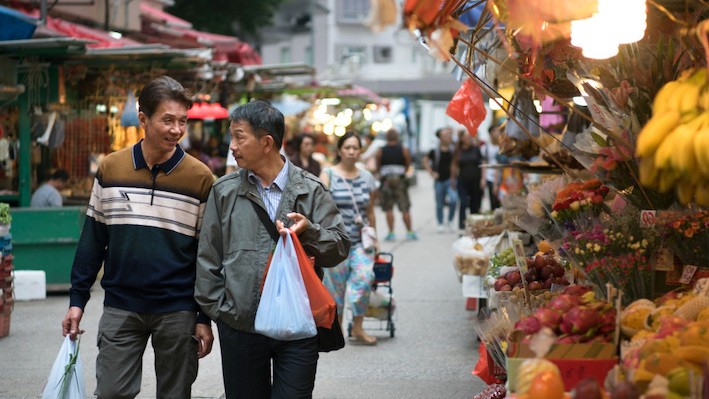 Two older Asian men walking in a market 