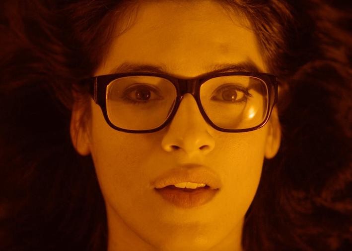 Still from 'The Garden Left Behind,' image courtesy of SXSW Film Festival A brunette white woman's face in orange hue with glasses