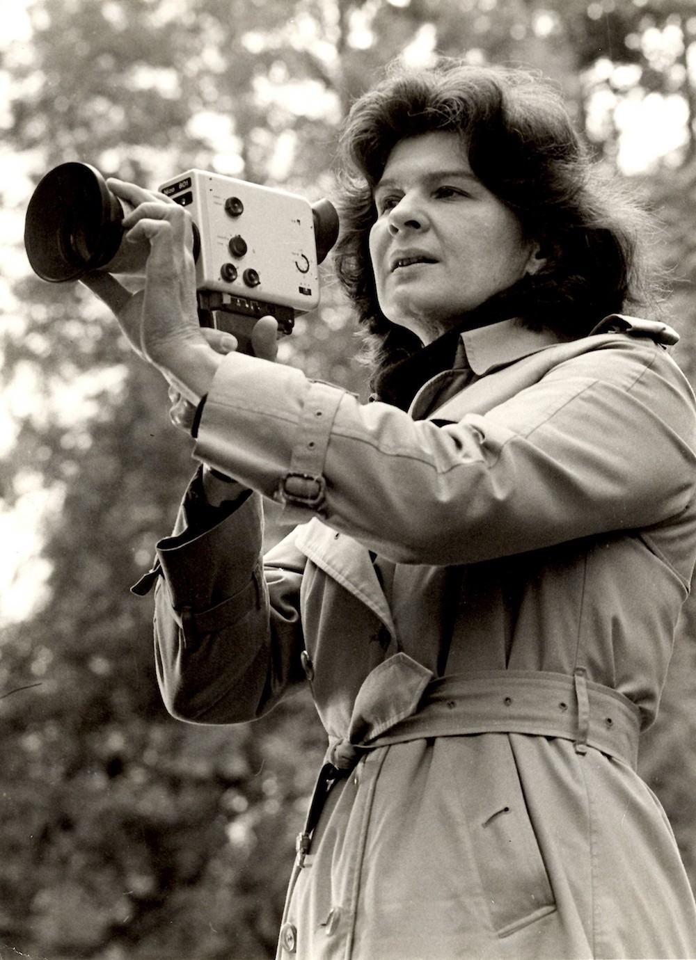 A sepia toned photo of a brown haired light skinned woman holding a camera.