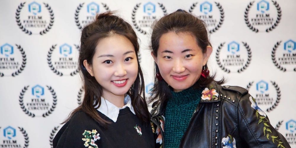 Two young Asian women smiling on the red carpet.
