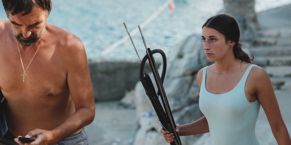 older man and younger woman in swimwear holding tools