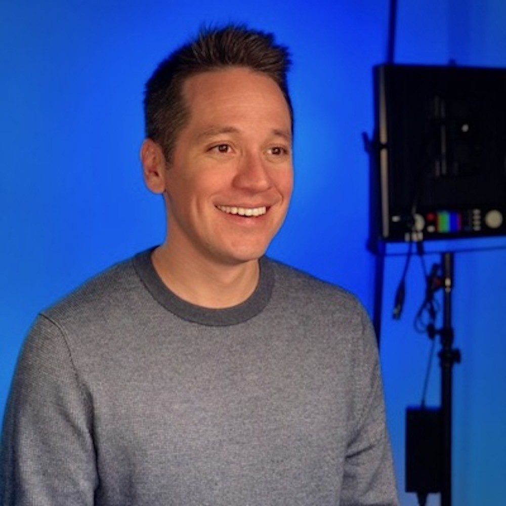 White man smiling on a blue screen TV set