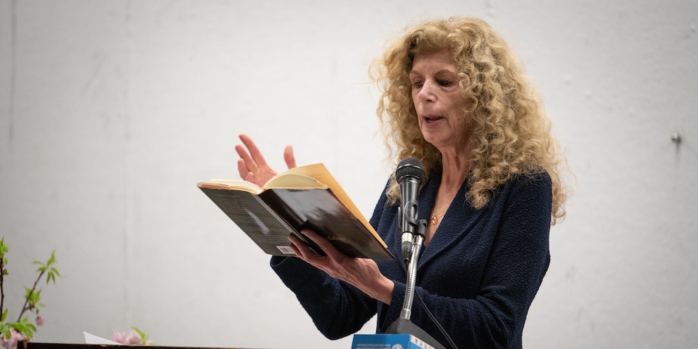 Woman reads from book on a podium. 